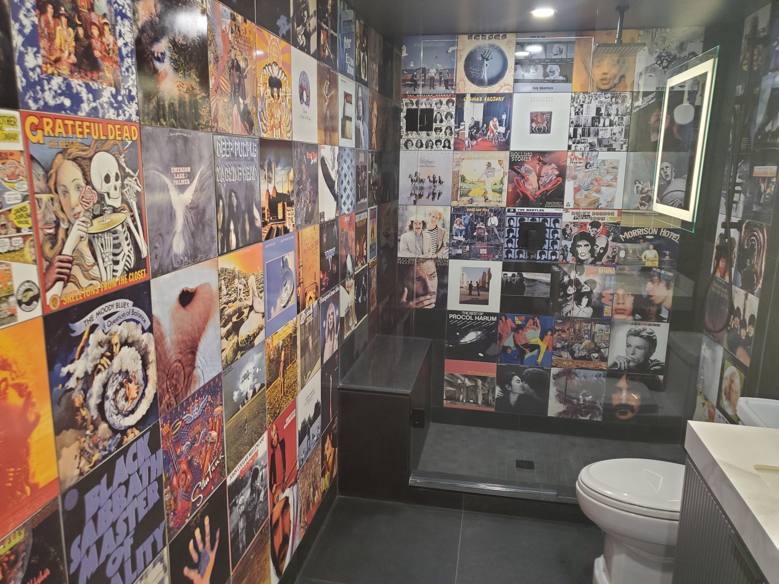 Private music room bathroom with custom printed album cover porcelain wall tiles around sink and toilet area