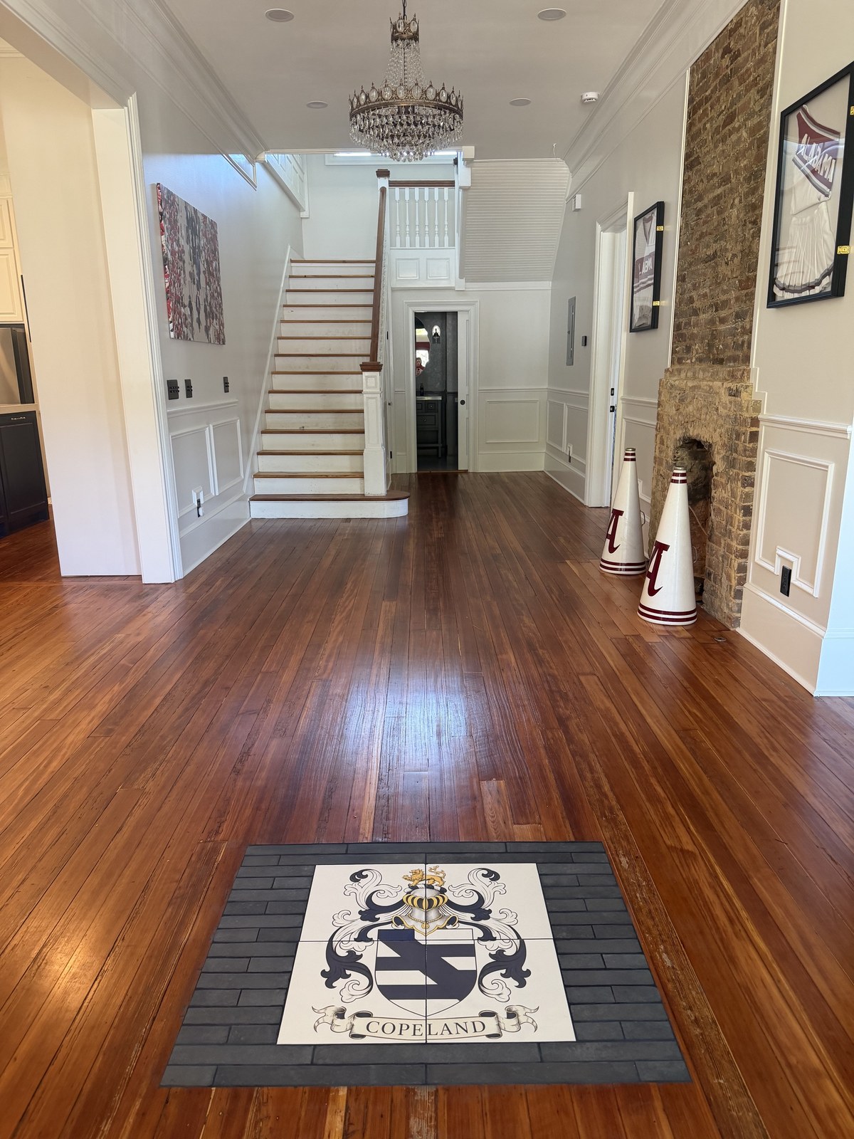 Copeland family crest printed on four floor tiles, framed by dark border tiles in a wood-floored foyer.